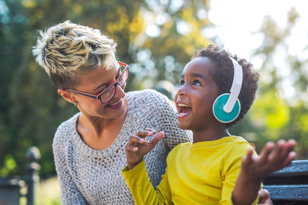 Happy mother smiling at her son with headphones on as they learn how to manage sensory seeking behaviors.