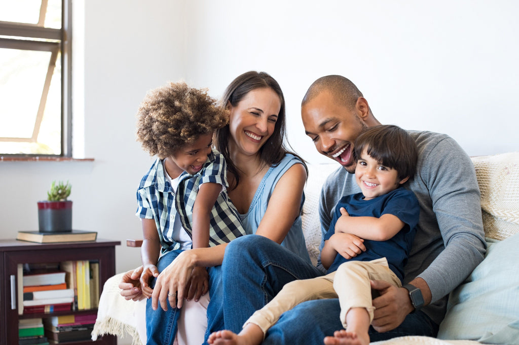 Family with autistic child sitting on couch laughing and having a good time together. 